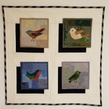 Die Vögel stehen auf einem Untergrund den ich im Stil eines Boro Quilts angefertigt habe. Ich habe sie darauf appliziert. Die einzelnen Quadrate werden mit Klettband auf dem Quiltuntergrund befestigt. Somit sind sie leicht austauschbar und können durch andere Motive ersetzt werden.